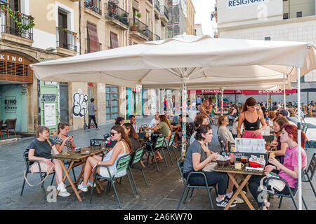 Barcellona Spagna,Catalonia Ciutat Vella,El Raval,Kino, ristorante,tavolo esterno,ombrello,occupato,al fresco,pranzo,uomo,donna,giovane adulto,studenti,cameriera, Foto Stock