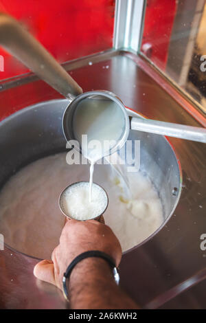 Versando Turca tradizionale bevanda Ayran in metallo vintage vecchia coppa di vetro. Ayran fatta con yogurt e acqua Foto Stock