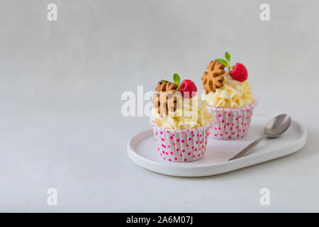 Natale tortine o muffin con panna e lampone, su sfondo concreto, tonica Foto Stock