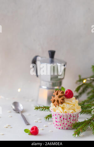 Natale tortine o muffin con panna e lampone, oltre l'Abete rami sfondo, tonica Foto Stock
