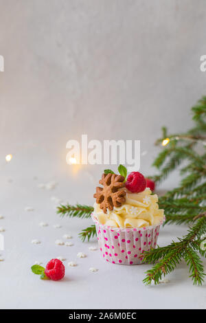 Natale tortine o muffin con panna e lampone, oltre l'Abete rami sfondo, tonica Foto Stock