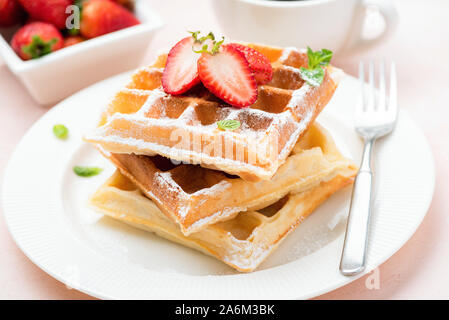 Cialde belghe con fragola e zucchero in polvere sulla piastra bianca. Sweet Food, dessert Foto Stock