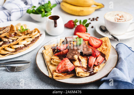 Crepe al Cioccolato, fragola e banana. Gustosi cibi dolci e dessert serviti nel ristorante. Blini con lo sciroppo al cioccolato e frutta Foto Stock