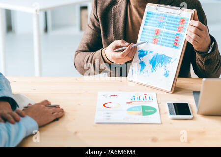 Uno dei due economisti puntando al documento finanziario mentre spiegando grafico Foto Stock