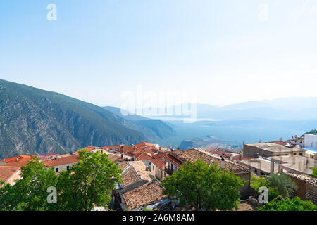 Vista dalla famosa città di Delphi fino alla città costiera di Itea su terracotta caratteristico tetto di tegole tops. Foto Stock