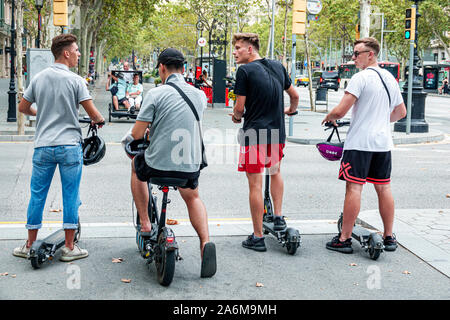 Barcellona Spagna,Catalonia Passeig de Gracia,quartiere dello shopping,ampio marciapiede,attraversamento di strada,uomo,amici,giovani adulti,scooters elettrici passo,in attesa di fo Foto Stock