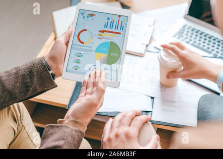 Giovane maschio economista con touchpad rivolti a schema finanziario sullo schermo Foto Stock