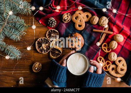 Ragazza con la tazza con una bevanda calda circondata da tradizionali xmas cibo e simboli Foto Stock