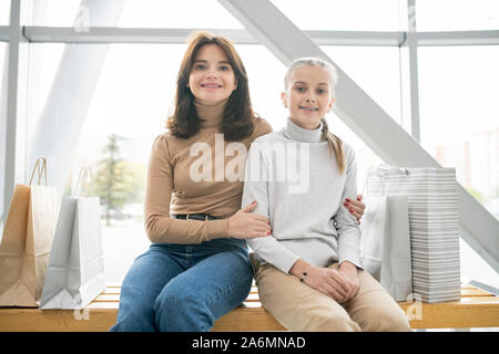 Piuttosto giovane madre e la sua figlia carino in informale in appoggio dopo lo shopping Foto Stock