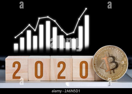 I numeri 2020 su cubi di legno con una moneta bitcoin con un grafico. Il concetto di crescita cryptocurrency nel nuovo anno. Close up. Foto Stock