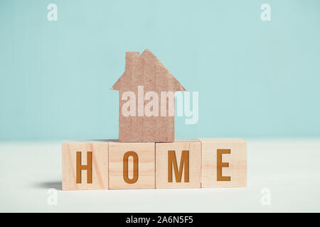 Abstract casa di cartone su cubi di legno con l'iscrizione. Close up. Tonica. Foto Stock