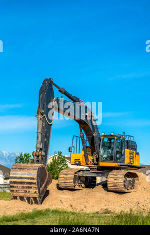 Close up di un escavatore con braccio e benna tracce continue sulla parte superiore del suolo Foto Stock