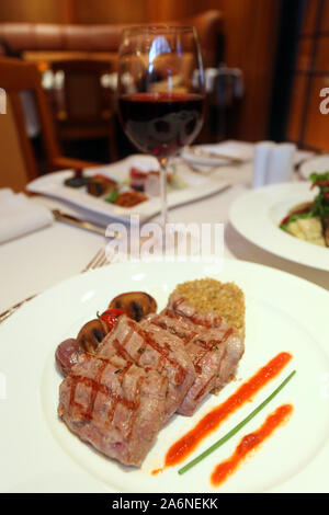 Bistecca con patate con mais e il vino rosso sul ristorante tavolo. Foto Stock