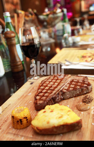 Bistecca con patate con mais e il vino rosso sul ristorante tavolo. Foto Stock