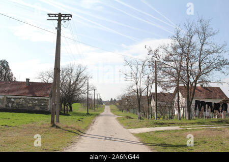 Trascurato street in semi deserte e decadeva villaggio di Rastina, in Serbia, con le vecchie aziende agricole e i campi sul lato. Rastina è un tipico villaggio o Foto Stock