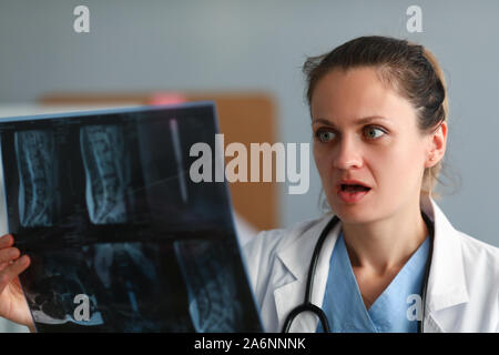 Excited donna medico tenere pellicola a raggi x in mano contro Foto Stock