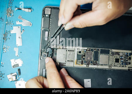 Le mani del lavoratore di fabbricazione che mostra il processo di creazione di fotocamera nel computer tablet Foto Stock