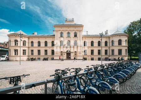 Oslo, Norvegia - 24 Giugno 2019: fila di città le biciclette parcheggiate le biciclette in affitto vicino a ONG del vecchio edificio. Ora è utilizzato oggi dall'Accademia di Belle Arti. Foto Stock