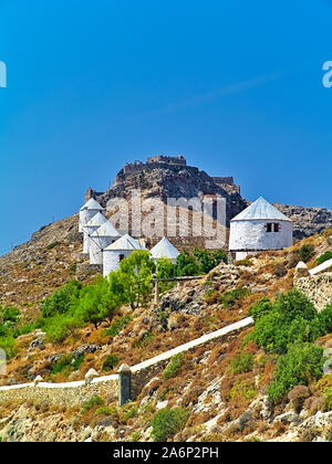 Bella bianco tradizionali mulini a vento sulla collina di Leros Island, Grecia. Il castello medievale di Panteli Panteliou o sulla collina. Foto Stock