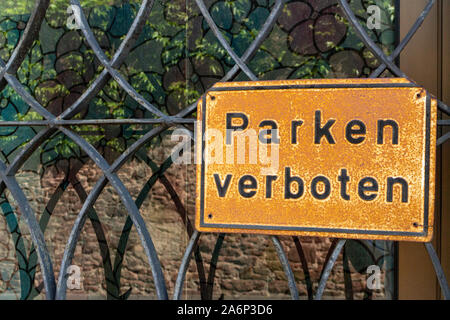 Vecchio weathered e rusty segno davanti a una finestra con il vecchio decorativo griglia in metallo con le parole "Parken verboten' che significa 'nessun parcheggio' in tedesco l Foto Stock