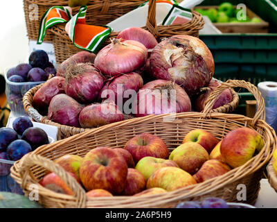 Cestini di vimini con le cipolle rosse e mele in vendita in un mercato agricolo Foto Stock
