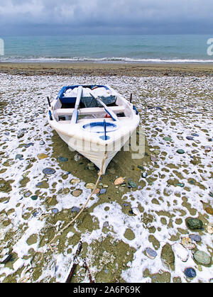 Paesaggio invernale barca bianca su una spiaggia coperta di neve, Pieria, Grecia Foto Stock