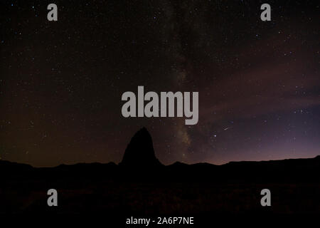 Questa è una vista del cielo notturno con la silhouette di un red rock monolito noto come il Tempio del Sole, nel Parco nazionale di Capitol Reef, Utah, Stati Uniti d'America. Foto Stock