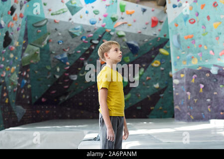 Giovanissimo sportivo in activewear in piedi nel centro della sala di arrampicata Foto Stock