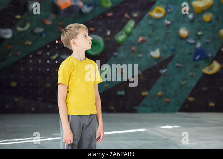 Attiva contemporaneo scolaro in giallo maglietta e pantaloni grigi Foto Stock