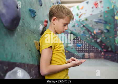 Stanco o triste youngster in giallo t-shirt appoggiata contro arrampicata attrezzature Foto Stock