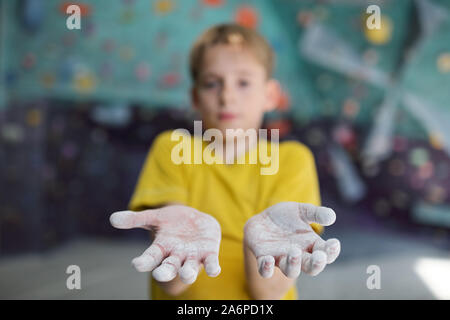 Scolaro che mostra le sue mani coperte con talco mentre in piedi nella parte anteriore della fotocamera Foto Stock