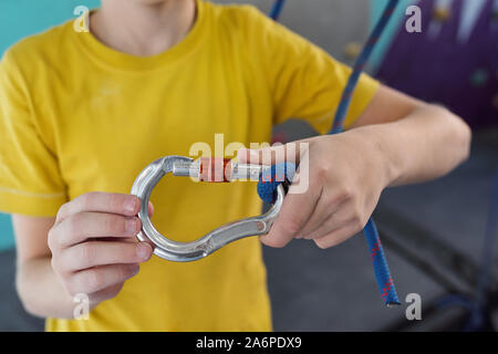 Mani di scolaro in giallo t-shirt holding moschettone arrampicata sulla fune Foto Stock