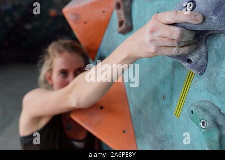 La mano del giovane scalatore femmina tenendo da parte di una delle piccole pietre artificiali Foto Stock