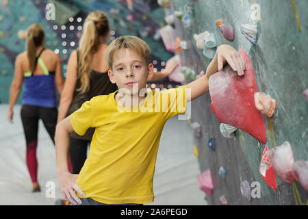 Ragazzo in activewear in piedi dalla telecamera e appoggiata da arrampicata attrezzature Foto Stock