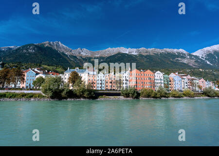 Vista panoramica di variopinti edifici nella città austriaca di Innsbruck con il fiume Inn in primo piano mountainsof e sullo sfondo le Alpi o Foto Stock