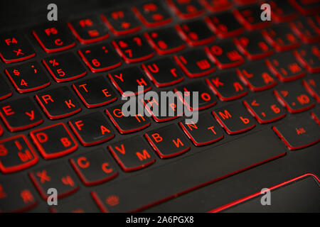 Close up rosso LED retroilluminato laptop computer tastiera con doppio alfabeto, Inglese e cirillico, ad alto angolo di visione Foto Stock