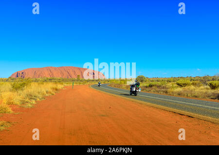 Uluru, Territorio del Nord, l'Australia - Agosto 25, 2019: motociclisti sul saled strada che conduce a Uluru Ayers Rock in Uluru-Kata Tjuta National Park Foto Stock