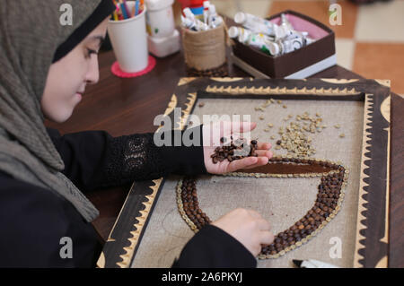 (191028) -- GAZA, 28 ottobre 2019 (Xinhua) -- artista Palestinese Hala Abu Qaoud fa arte pezzi utilizzando chicchi di caffè a casa sua nel sud della striscia di Gaza città di Rafah, 28 ottobre 2019. Abu Qaoud, 20, studi belle arti presso una università locale nella Striscia di Gaza. Lei vende la sua arte pezzi su le piattaforme di social media. (Foto di Khaled Omar/Xinhua) Foto Stock