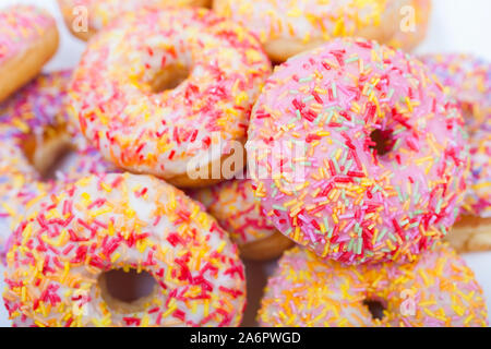 Donuts o ciambelle con glassa colorata o glassa e spruzza fotografato su sfondo bianco Foto Stock