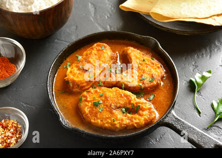 Close up di pesce al curry in padella in pietra nera tabella. Stile Indiano cibo Foto Stock