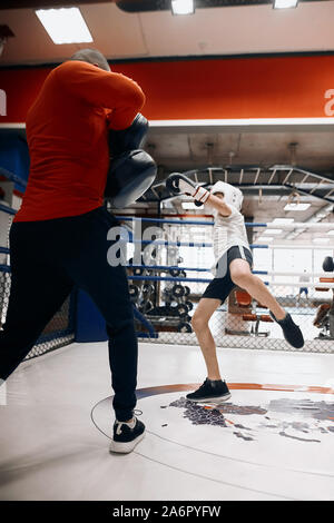 Ambizioso ragazzo è bravo a kickboxing, bambino preparando per un concorso a piena lunghezza foto Foto Stock