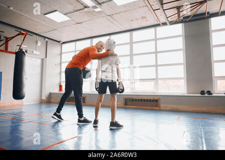 Felice positivo allegro coach cheerfing il ragazzo alto prima del combattimento, supporto , a lunghezza piena vista posteriore foto. spazio copia Foto Stock