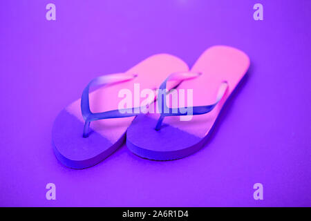 Rosa flip flop su sfondo viola. Laici piana, orizzontale shot, vicino. Estate, vacanze, spiaggia, scarpe concept Foto Stock