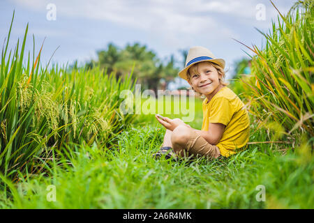 Ragazzo giocando phone seduto sull'erba verde, moderno bambini, nuove tecnologie, i bambini della dipendenza sul telefono Foto Stock