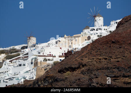 Una vista dal basso cercando fino a Oia mulini a vento sulla scogliera vulcanica top blu chiaro ski in Santorini Foto Stock