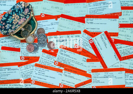 Un portamonete e denaro su una pila di biglietti ferroviari. Costo del viaggio in treno concetto. Foto Stock