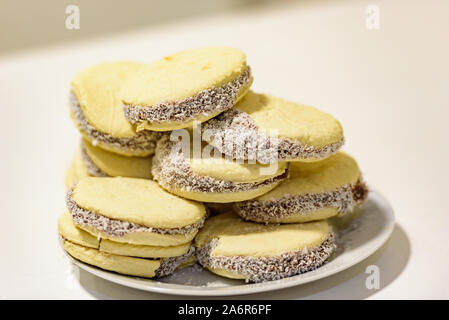 Accoppia e deliziosi biscotti argentini e uruguaiani alfajores con crema su carta primo piano sul tavolo. Orizzontale. Mate drink tradizionale in Uruguay Foto Stock