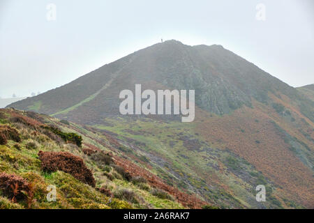 Burway collina vicino Church Stretton nello Shropshire in autunno la nebbia e bassa cloud con una figura in lontananza sul vertice Foto Stock