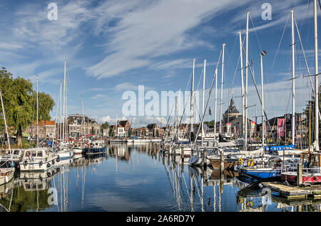 Enkhuizen, Paesi Bassi, 13 Settembre 2019: cielo blu, yacht moderno e facciate storiche si riflettono nei dello specchio d'acqua del porto interno mar Foto Stock