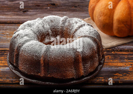 Muffin di zucca al buio su un tavolo in legno e zucca in background Foto Stock